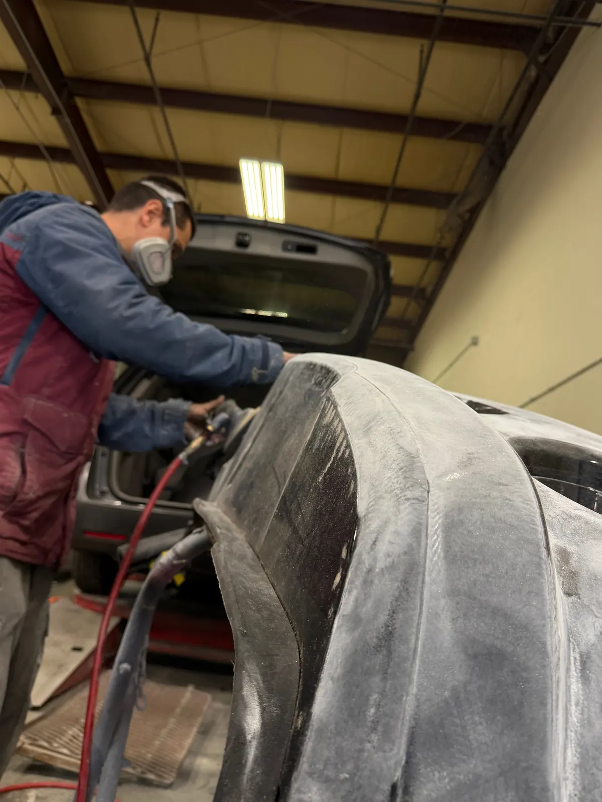 Technician sanding a bumper panel for refinishing