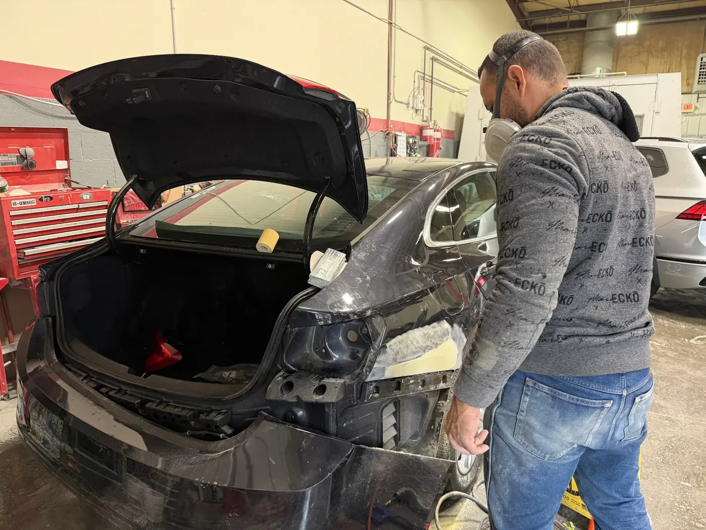 Best Finish technician finishing body work on a black sedan